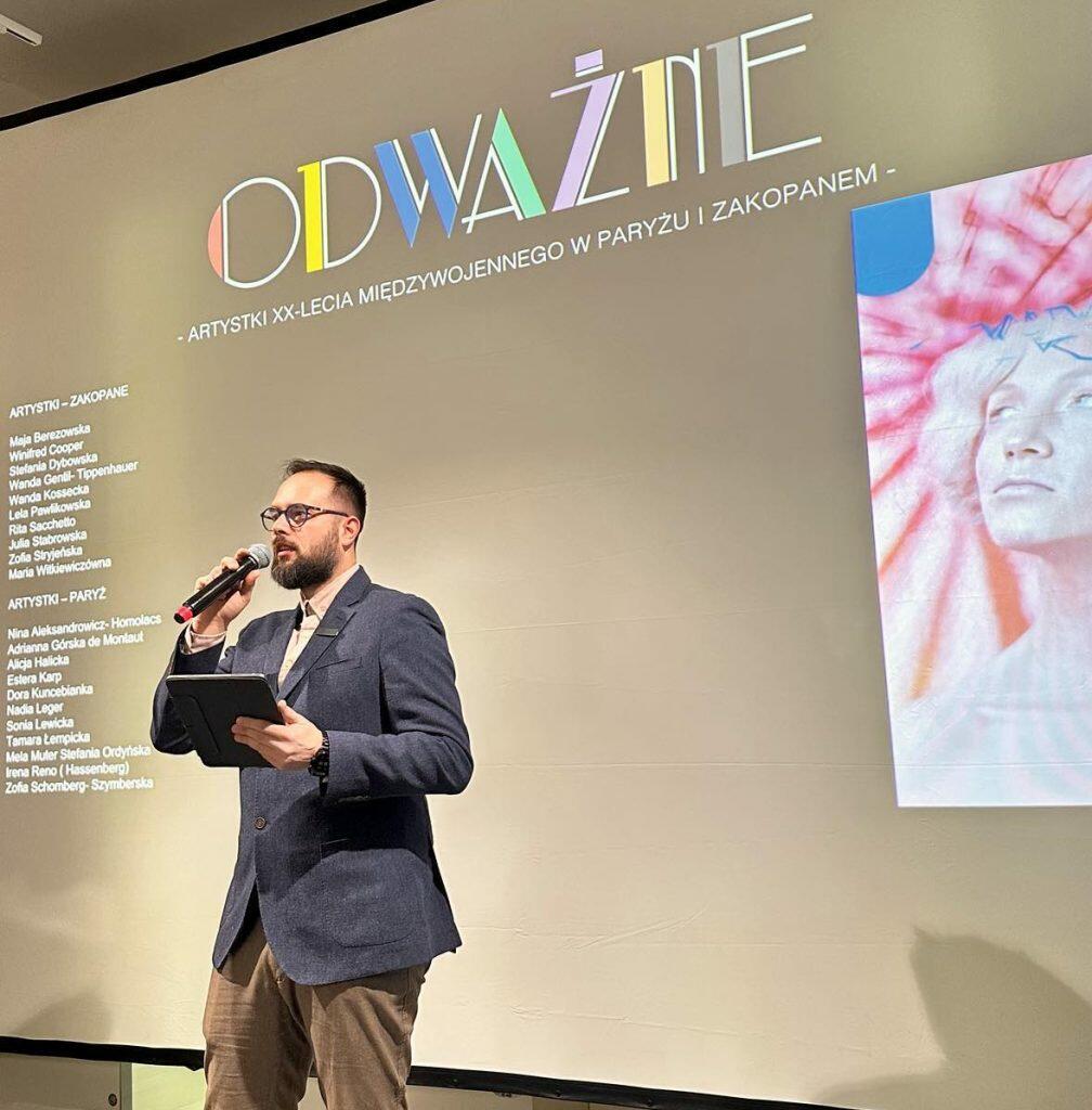 Dyrektor Muzeum przemawia w Muzeum na tle napisu ODWAŻNE