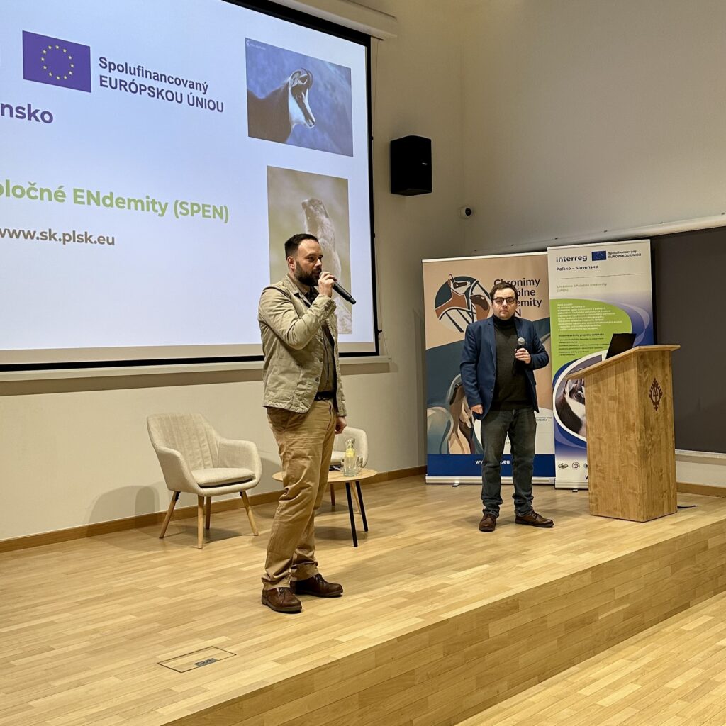 Otwarcie warsztatów eksperckich ,,Biobankowanie i monitoring endemicznych ssaków Tatr". Dyrektor Muzeum Michał Murzyn przemawia do mikrofonu, obok stoi Marcin Warchałowski. W tle prezentacja.