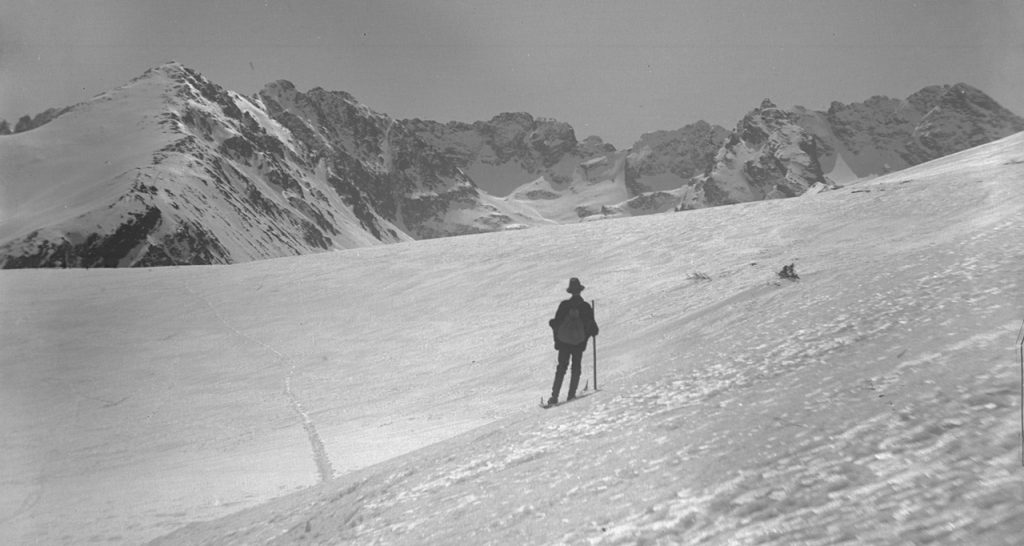 stare zdjęcie przedstawia narciarza na tle białych szczytów