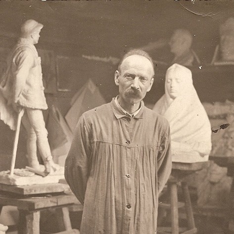 rzeźbiarz w pracowni po obu stronach jego rzeźby