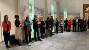 Osoby zaangażowane w przygotowanie wystawy w muzeum na tle eksponatów i czarnobiałych zdjęć wiszących na ścianie w części etnograficzno-historycznej