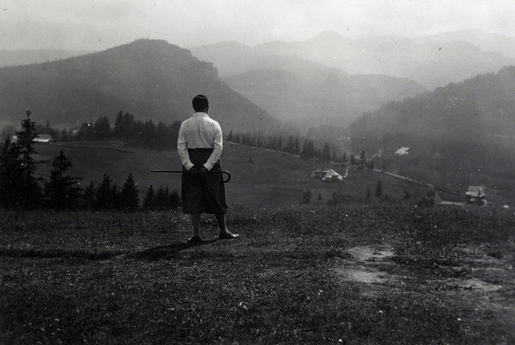 Czarno-biała fotografia przedstawia mężczyznę tyłem, podziwiającego górski widok
