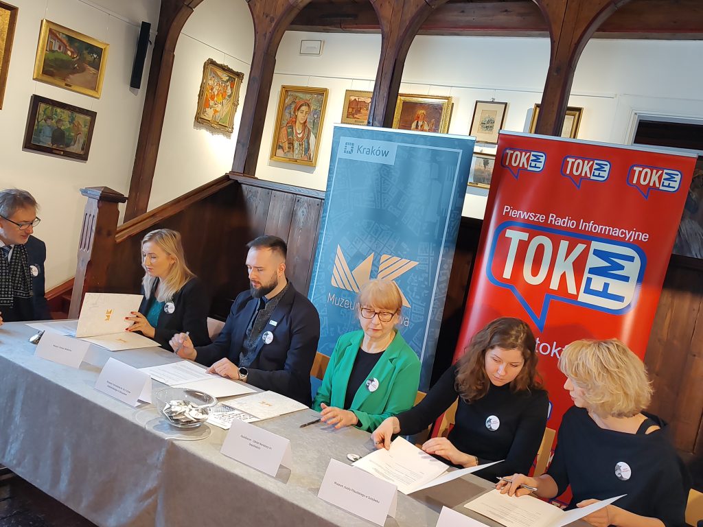 Sześć osób, 4 przedstawicieli i dwóch przedstawicieli instytucji kultury podpisuje umowę o współpracy. Siedzą przy stole w Muzeum w Bronowicach