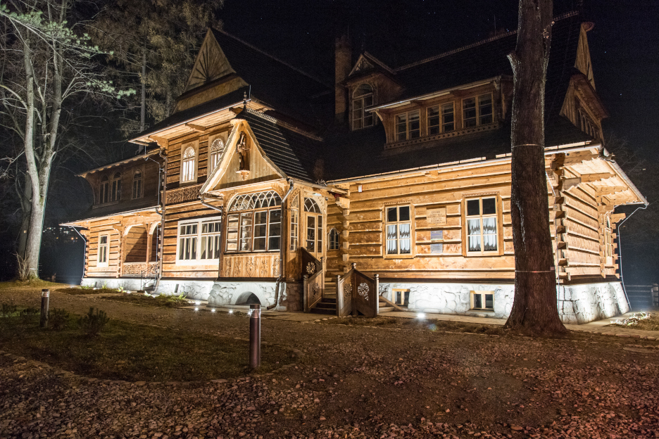 Koliba oświetlona nocą, zdjęcie całego budynku z frontu., fot. Michał Zieliński