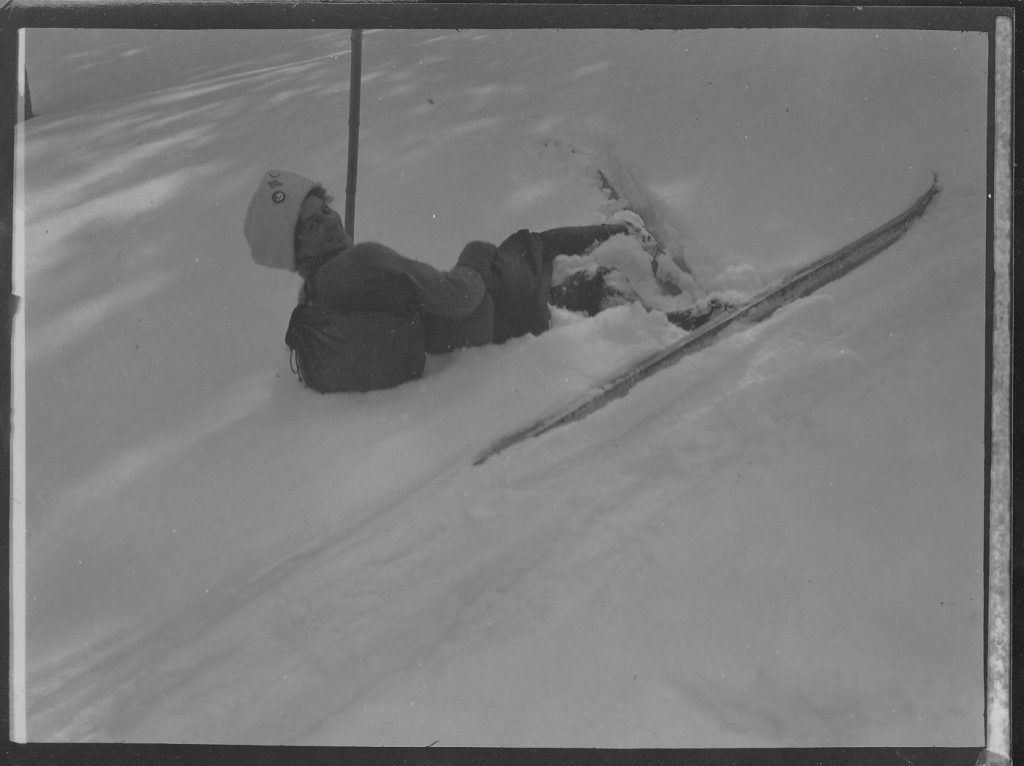 Czarno-białe zdjęcie, narciarza, który się wywrócił na wyciągu orczykowym.